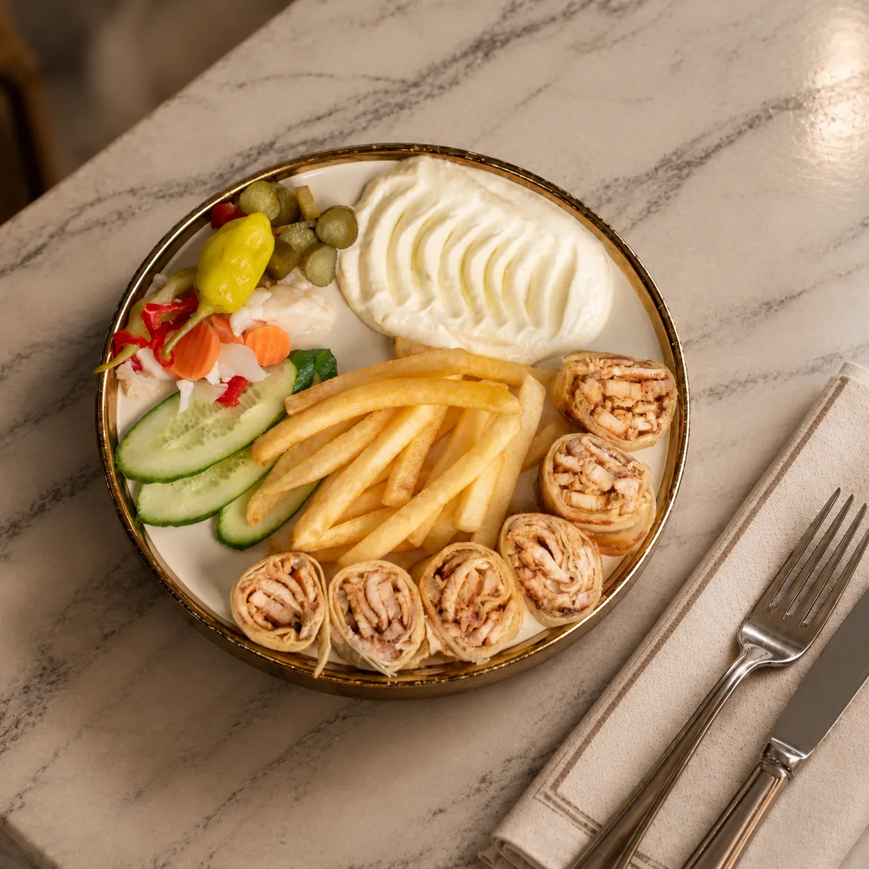 Chicken Shawarma Arabi sliced wrap rolls with fries, garlic sauce, pickles and cucumber on a marble table